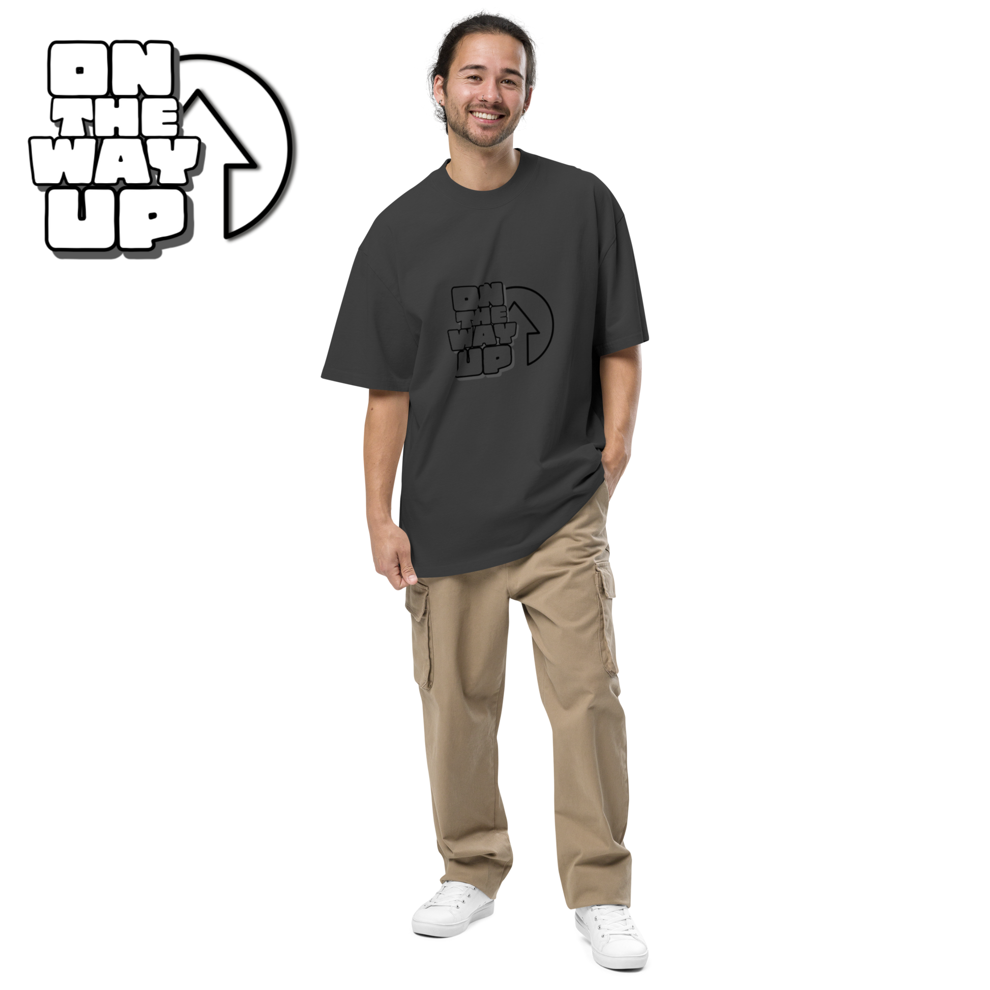 A person with a cheerful expression is standing, wearing an Oversized faded Large Print t-shirt from On The Way Up Apparel and beige cargo pants, posing against a black background. The same "ON THE WAY UP" text appears enlarged in the top-left corner.