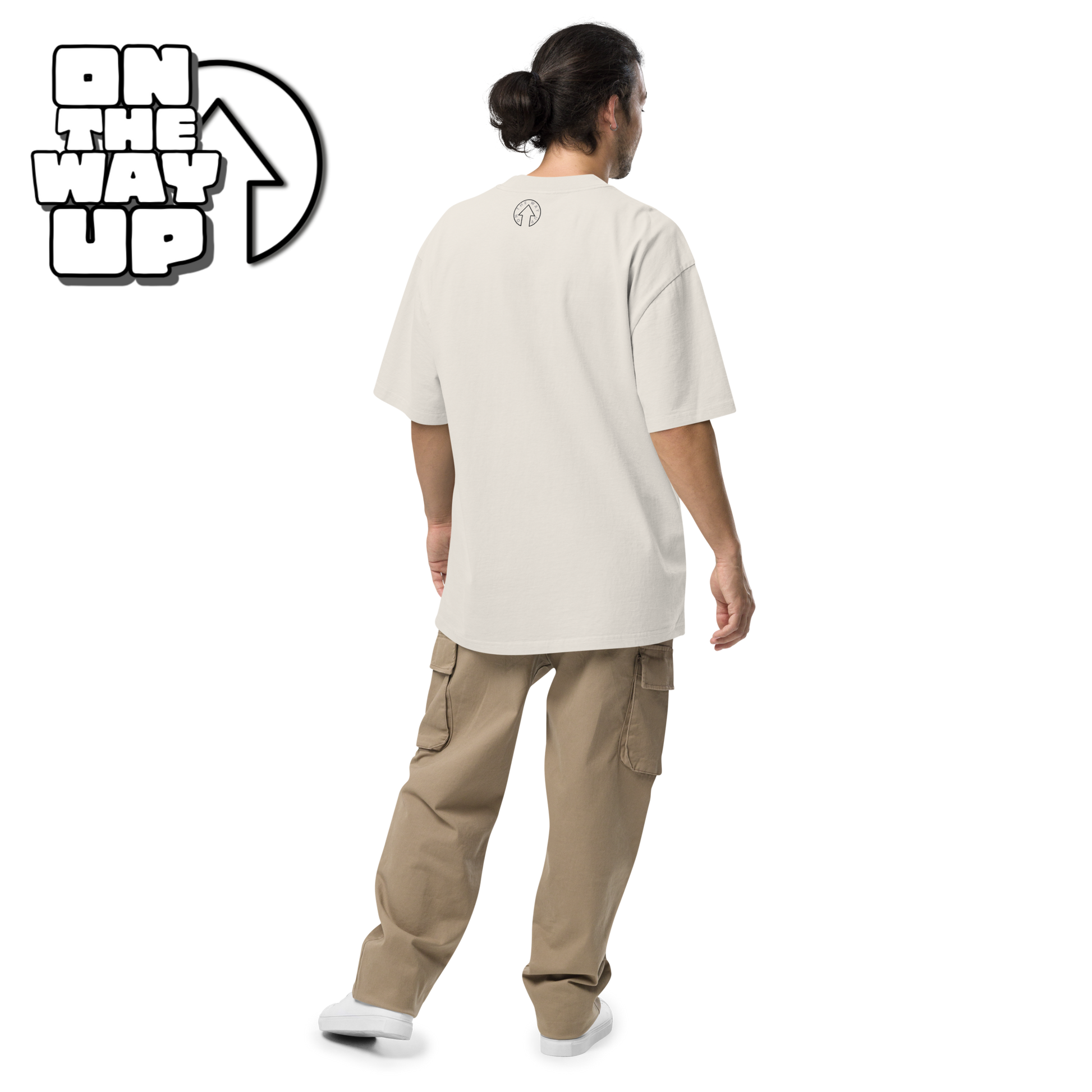 A person with long hair tied back is standing with their back to the camera. They are wearing an oversized faded Large Print t-shirt and beige cargo pants, paired with white shoes. Text in the corner reads "ON THE WAY UP Apparel.