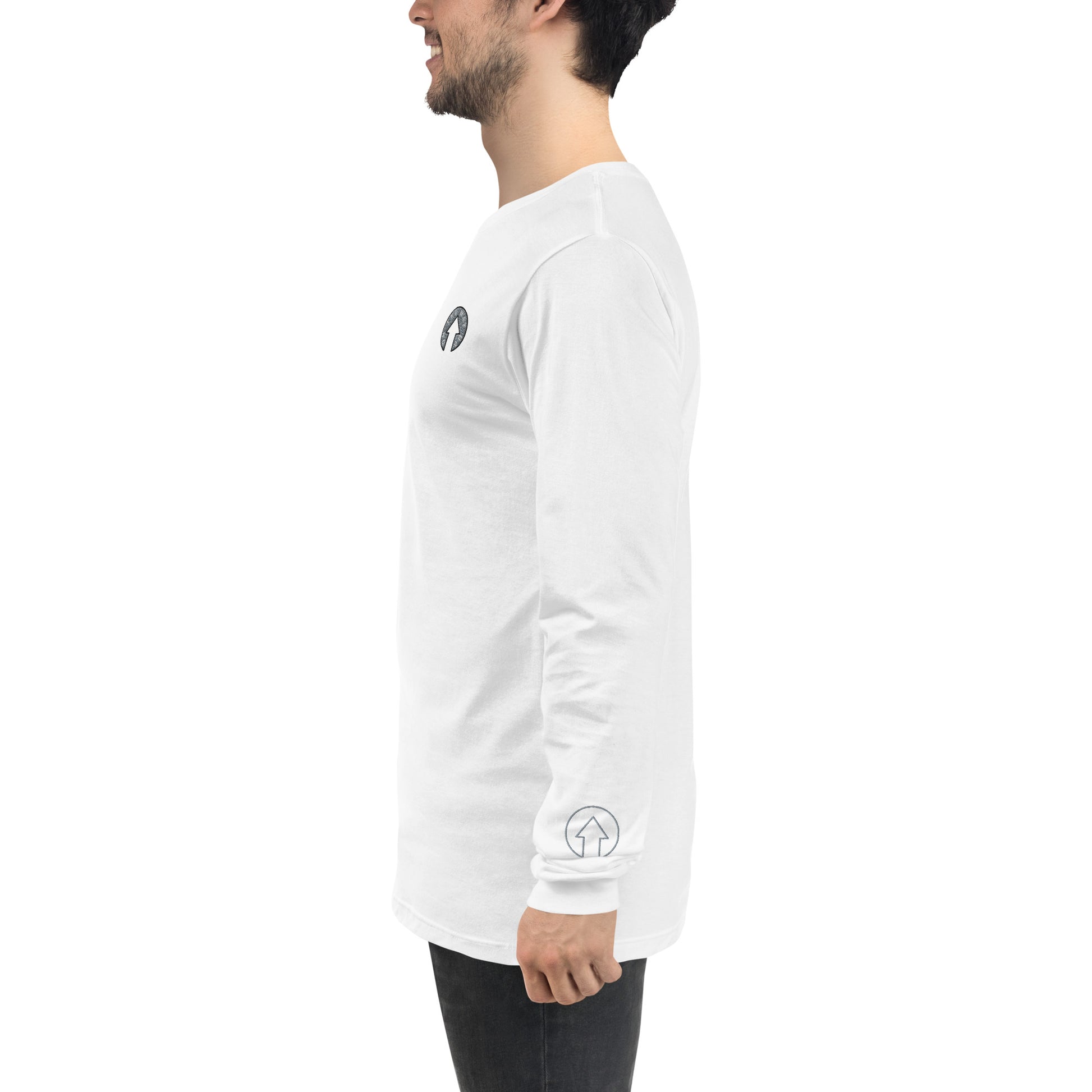 Side view of a man wearing an On The Way Up Apparel white long-sleeve shirt with a small black "Premium Quality" logo on the chest and another on the left sleeve, paired with dark jeans, standing against a white background.