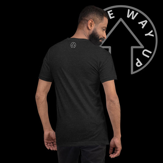 A man facing away from the camera, wearing an On The Way Up Apparel premium quality black T-shirt with a logo on the back, standing against a dark background with a stylized directional arrow symbol.