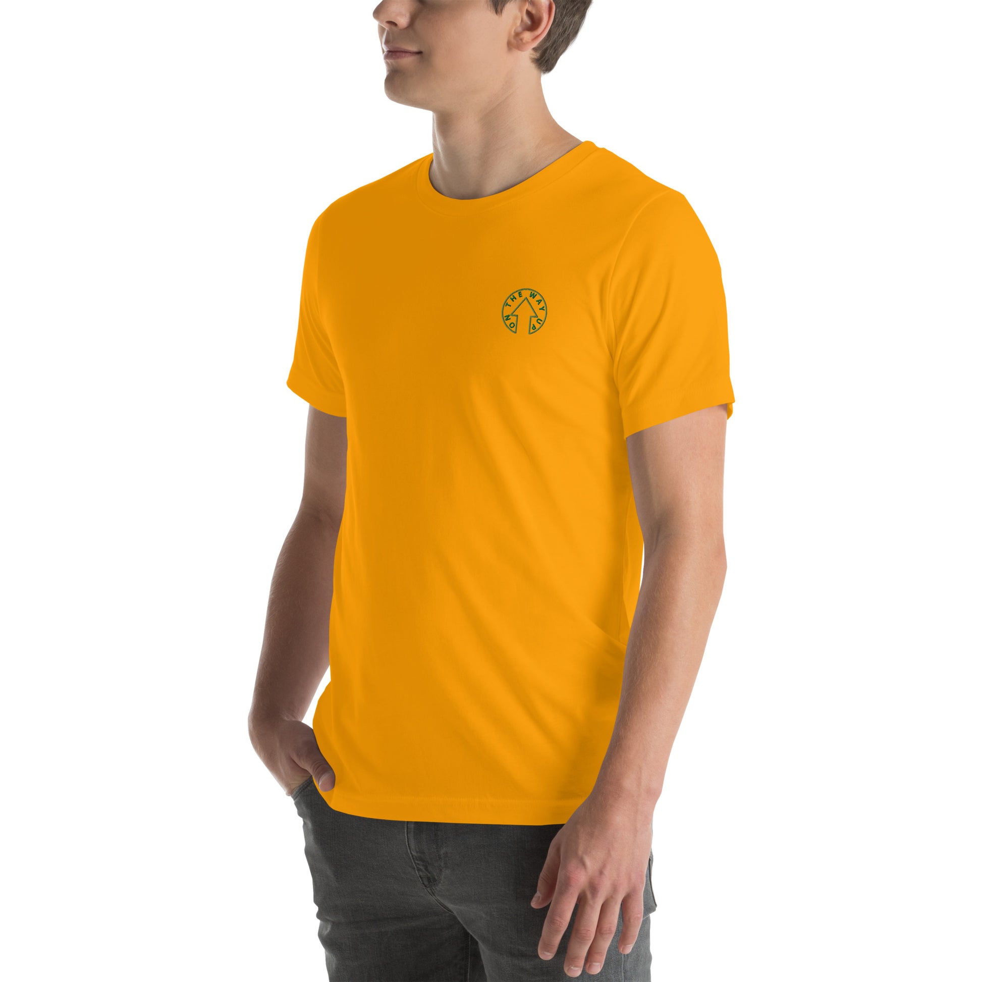 A man wearing an On The Way Up Apparel BE BOLD - On The Way Up Embroidered Logo T-shirt in bright yellow with a small circular logo on the left chest area, paired with gray jeans, standing in a side profile pose.