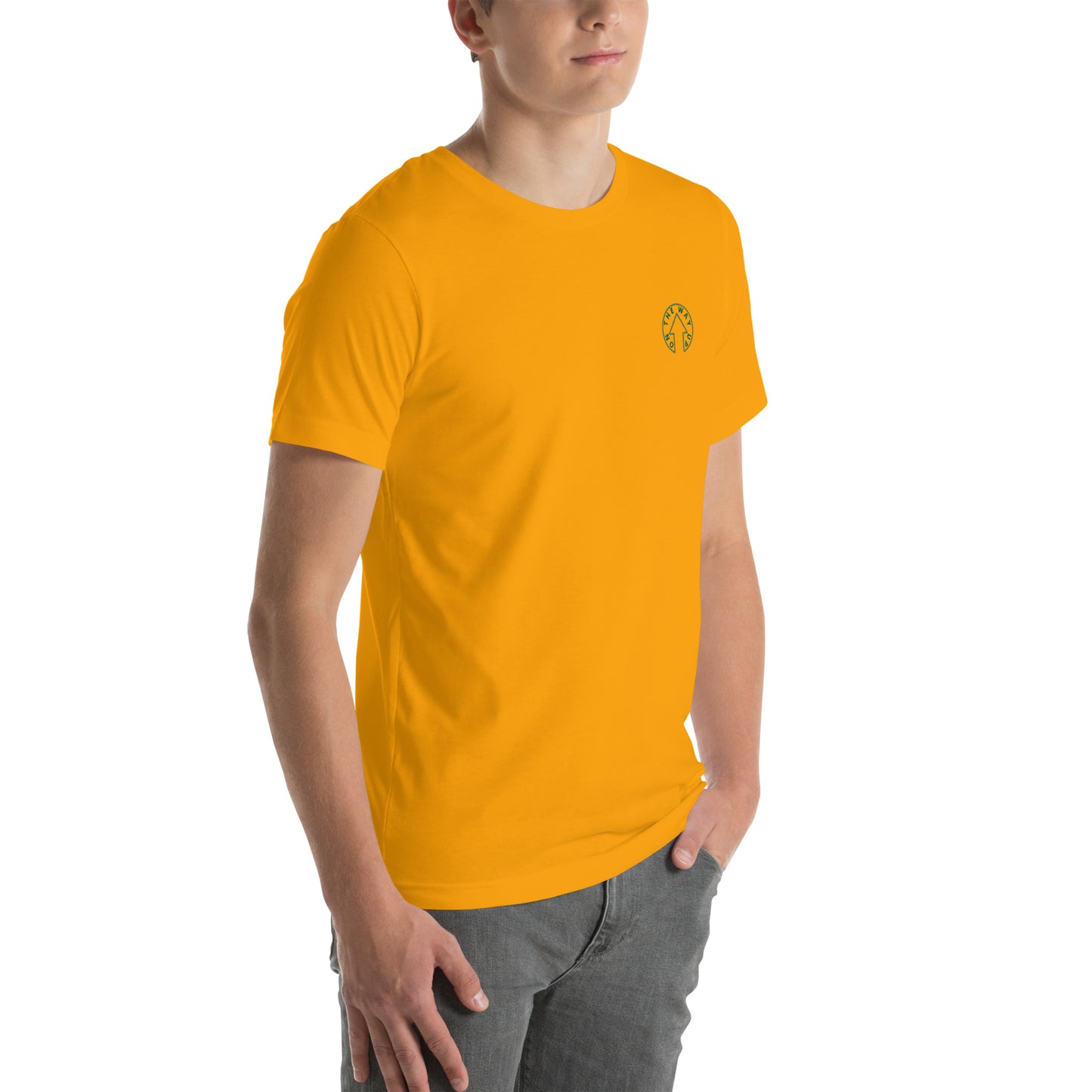 Young man in an On The Way Up Apparel BE BOLD - On The Way Up Embroidered Logo T-shirt in yellow, with a small embroidery on the left chest, standing against a white background. He wears gray pants and looks towards his right.