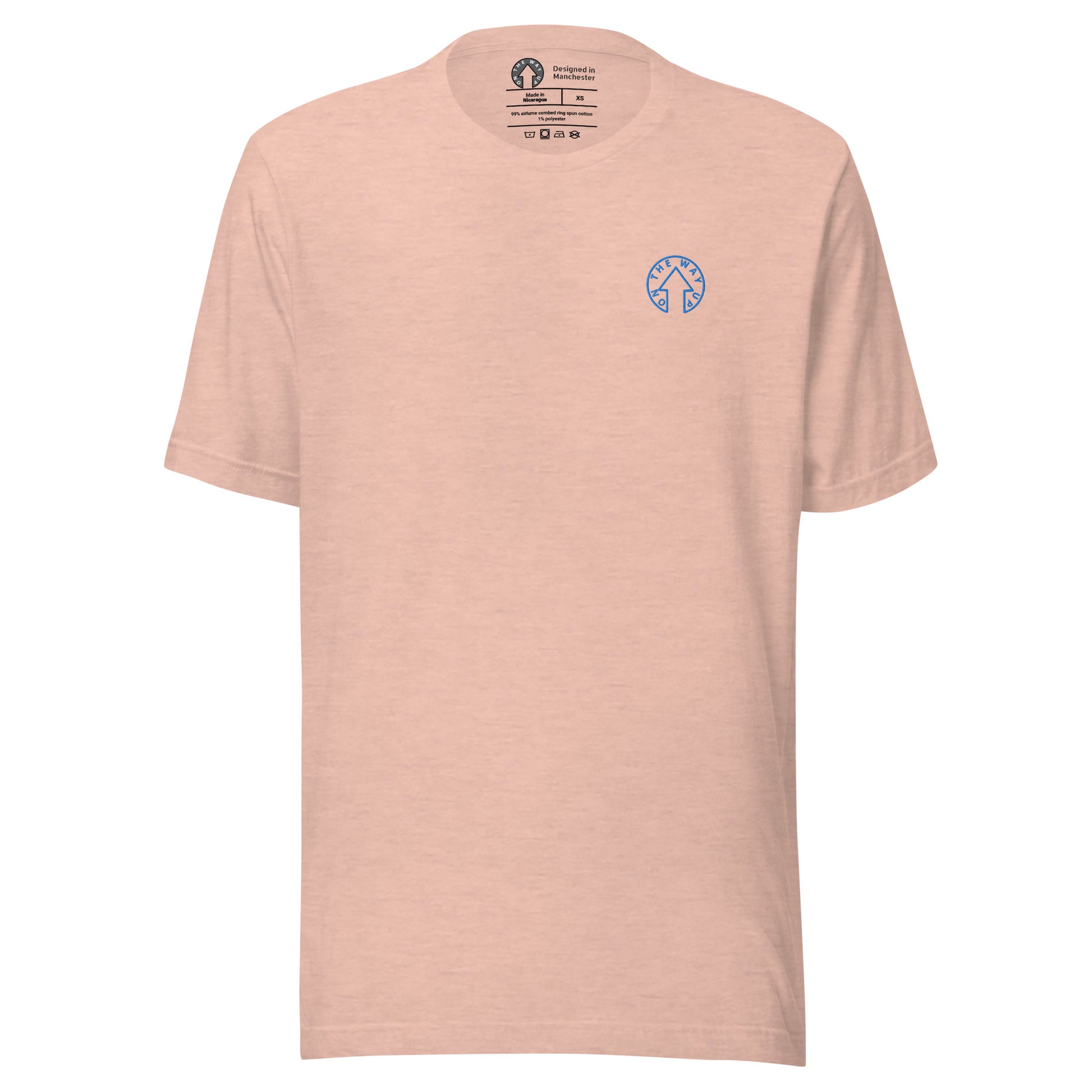 A plain light pink BE BOLD - On The Way Up Embroidered Logo T-shirt with a small blue logo on the left chest area, featuring what appears to be a round emblem with geometric shapes inside. This premium quality shirt showcases craftsmanship from Manchester.