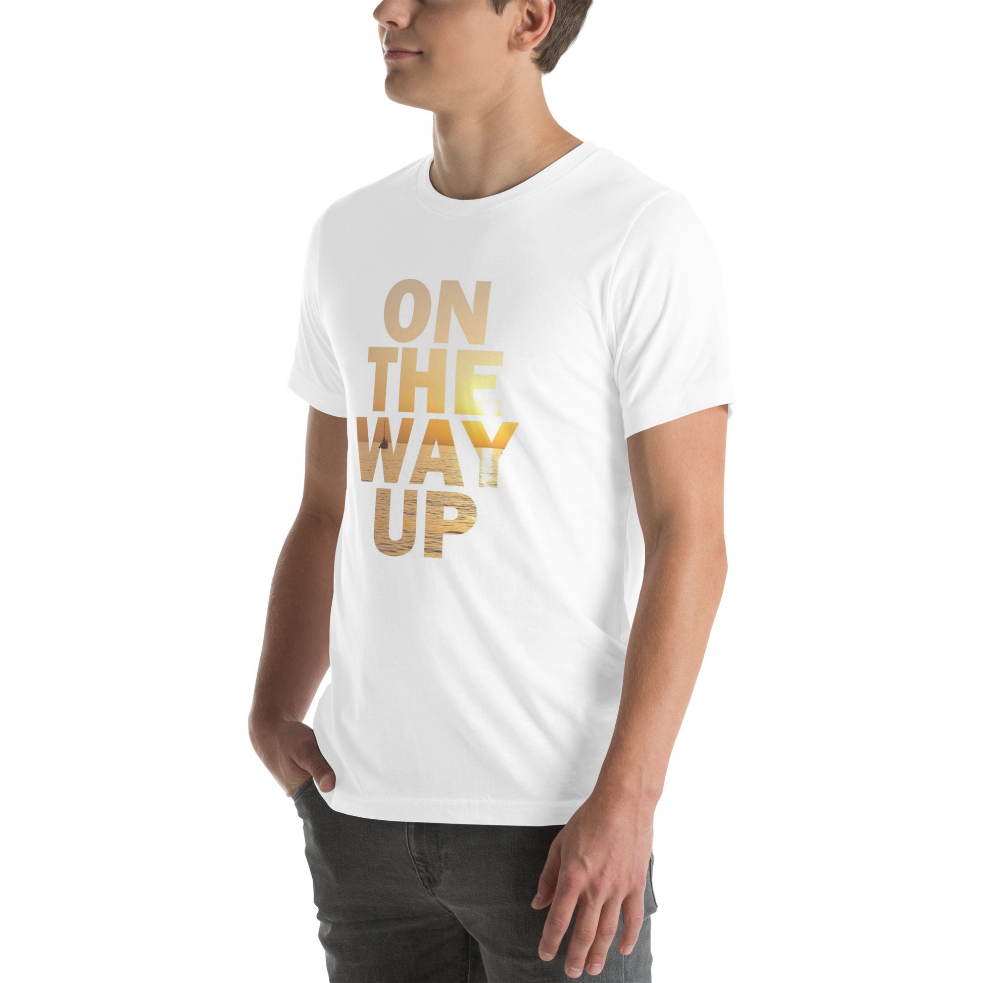 A person is wearing the Mambo Beach Sunset Tee from On The Way Up Apparel, featuring "ON THE WAY UP" printed in bold, gold letters on the front. The pre-shrunk, lightweight cotton fabric ensures a perfect fit. The person stands with one hand in their pocket, looking slightly to the side against a plain dark background.