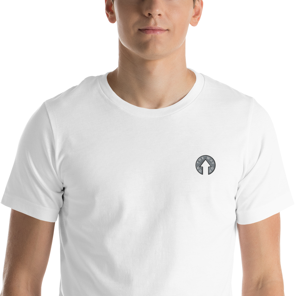 A young man wearing a Signature T-shirt White from On The Way Up Apparel, with a small black and white logo on the left chest, posing against a black background.