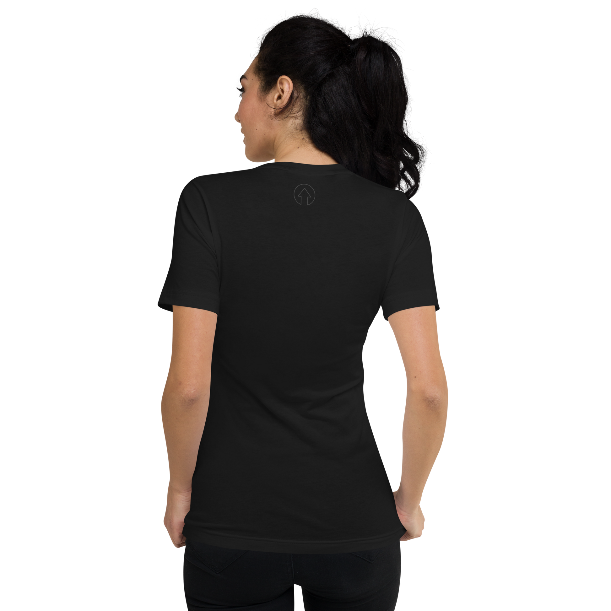 A woman stands with her back to the camera, wearing a plain black Signature Short Sleeve V-Neck T-Shirt from On The Way Up Apparel. Her dark hair is styled in a ponytail.