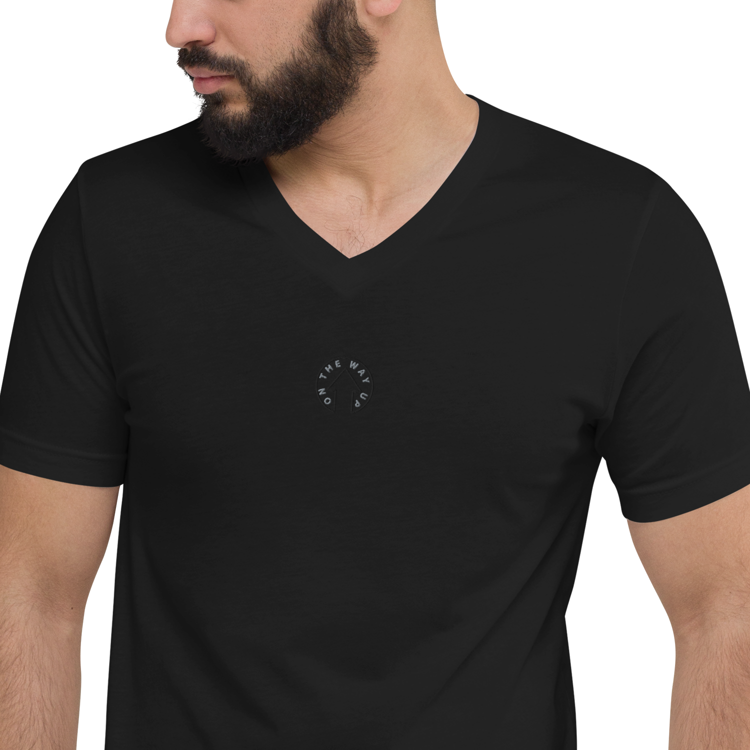 A man wearing an On The Way Up Apparel Signature Short Sleeve V-Neck T-shirt in black with a small, white compass design on the left side of the chest. He is facing to the right with a slight beard.