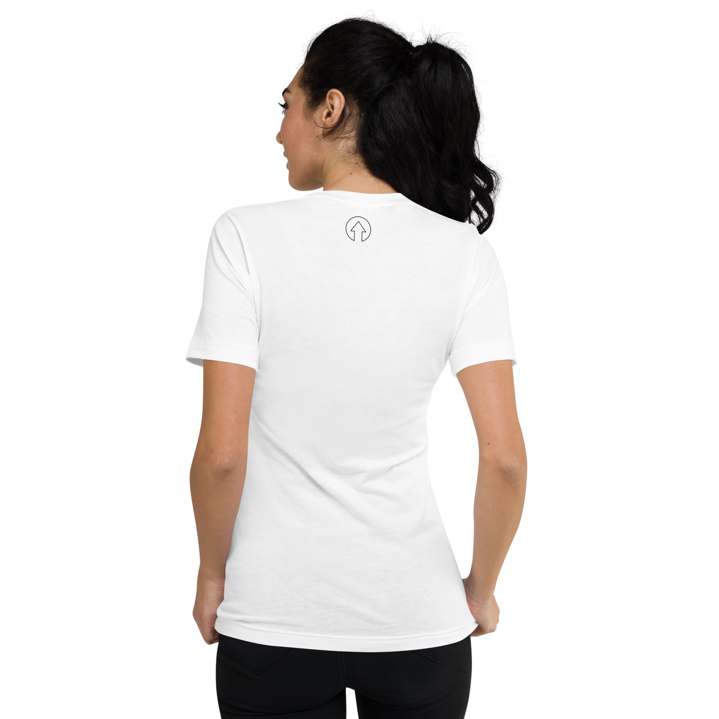 A woman is shown from the back, wearing a plain white Signature Short Sleeve V-Neck T-shirt with a small black "Manchester" logo on the upper back. She has dark hair tied back in a ponytail.