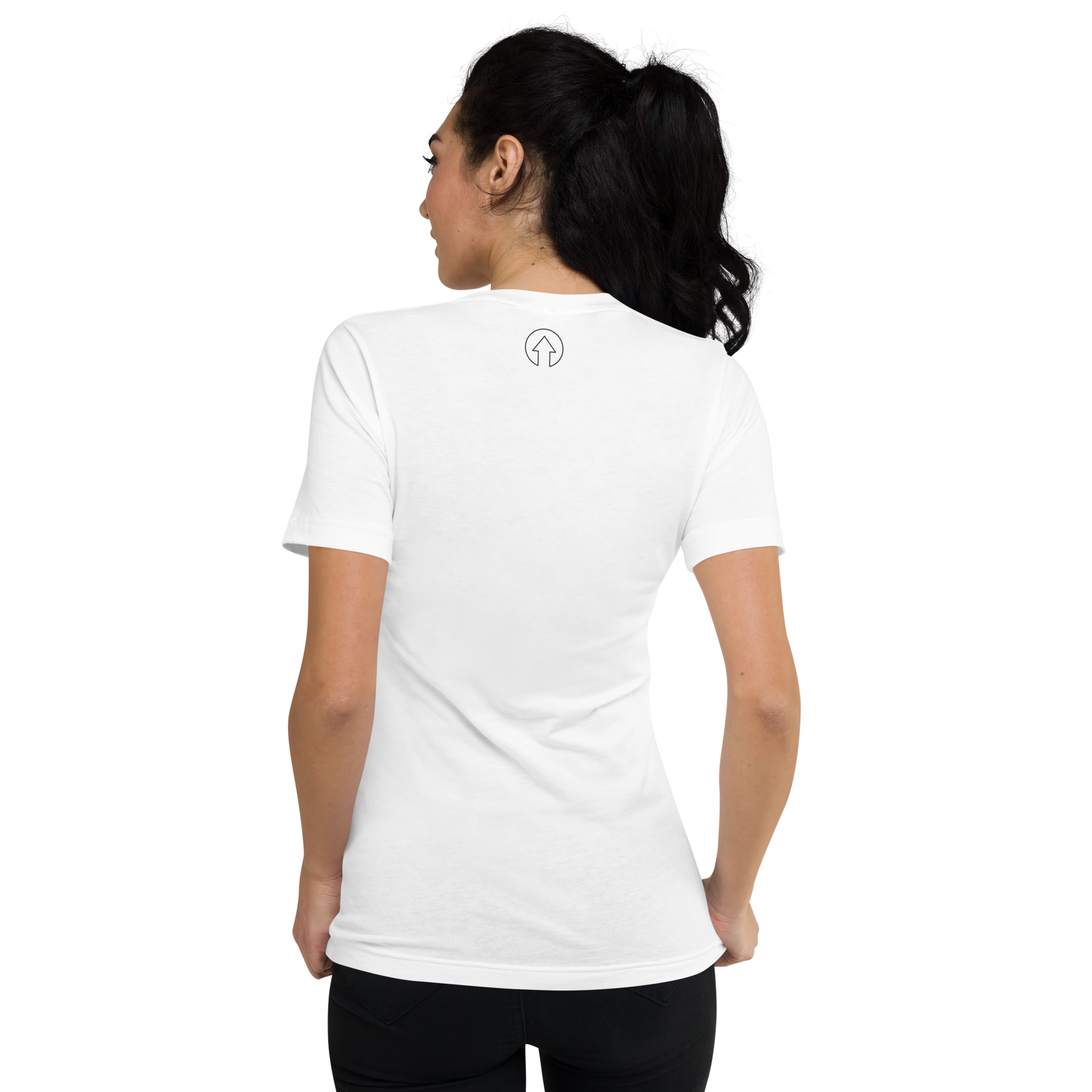 A woman is shown from the back, wearing a plain white Signature Short Sleeve V-Neck T-shirt with a small black "Manchester" logo on the upper back. She has dark hair tied back in a ponytail.