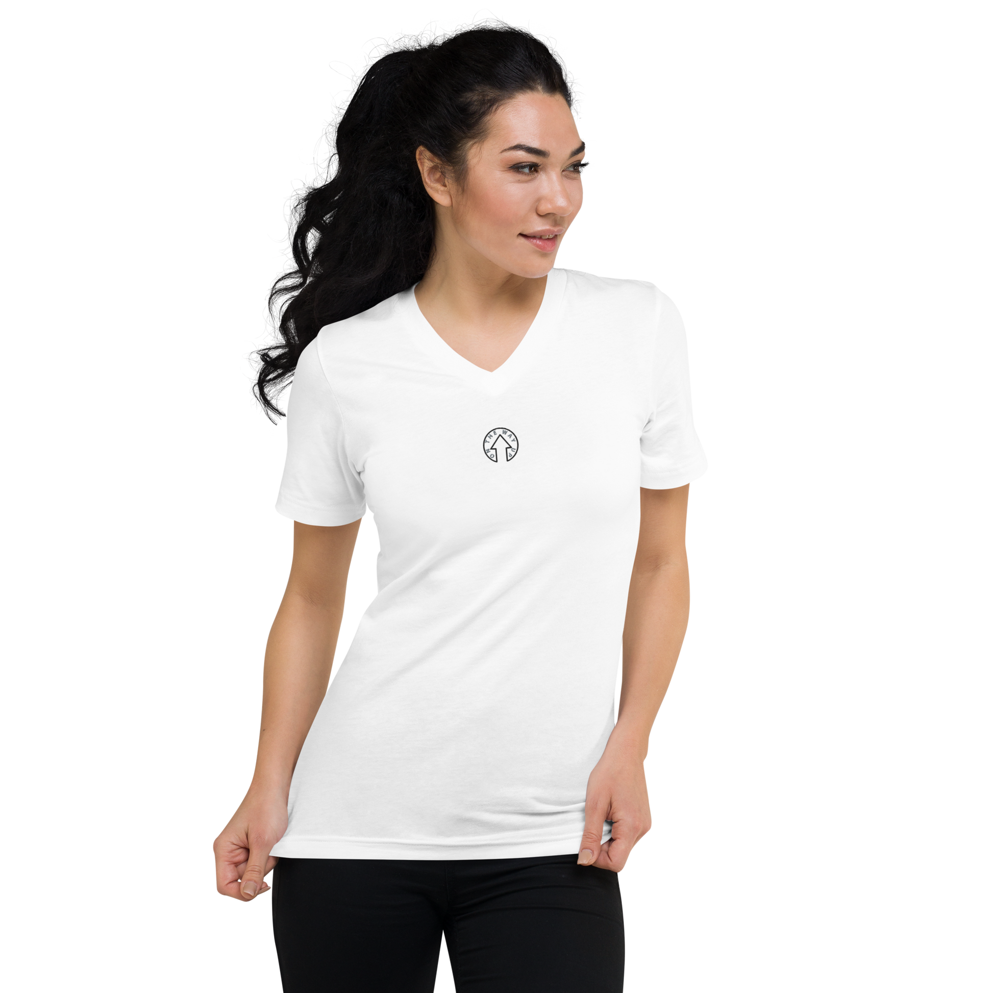 A woman with long, dark hair wearing an On The Way Up Apparel Signature Short Sleeve V-Neck T-Shirt in white with a small logo on the left chest, standing against a black background, looking to her right.