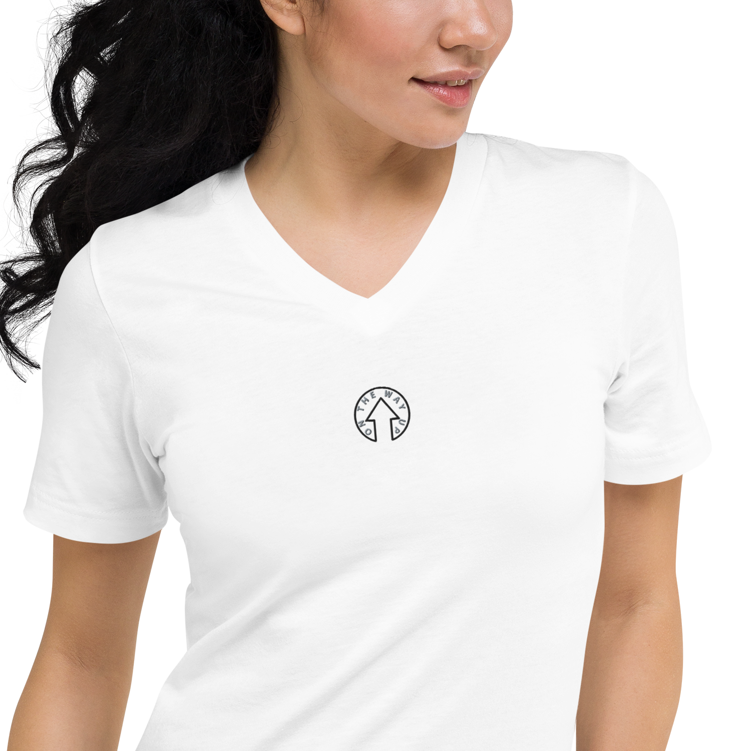 A woman wearing a plain white Signature Short Sleeve V-Neck T-shirt with a small black and white circular "Premium Quality" logo on the left chest area. She has curly dark hair and is looking to her right. Brand name: On The Way Up Apparel